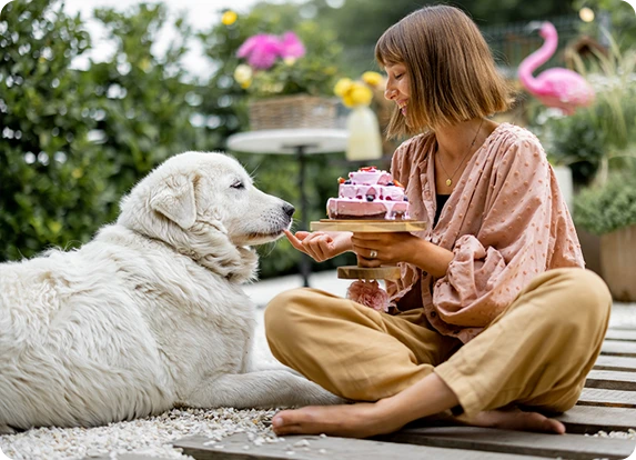 A woman feeding her dog some birthday cake