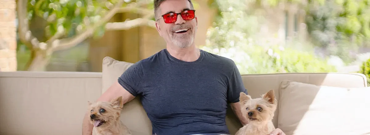 Simon Cowell on the couch with his two small dogs