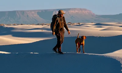 Man walking with his dog in white sands